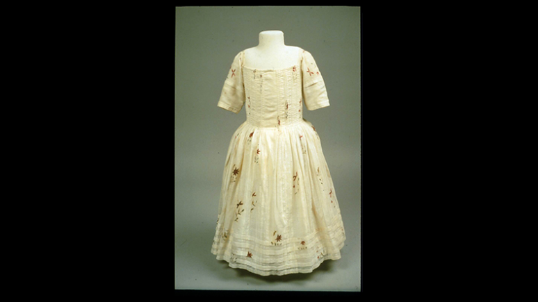 Robe de couleur crème avec des manches au coude et une jupe ample décorée d'un subtil motif floral.