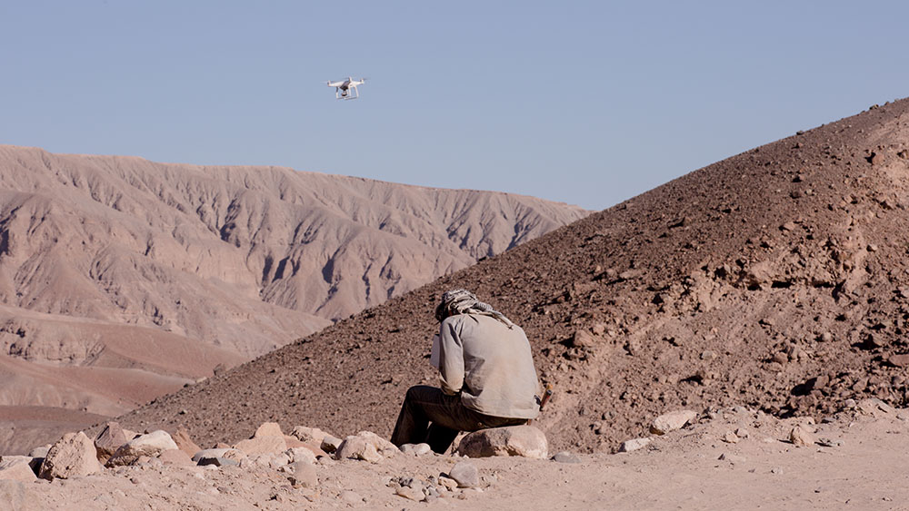 Man operating drone as it shoots video of an archaeology site