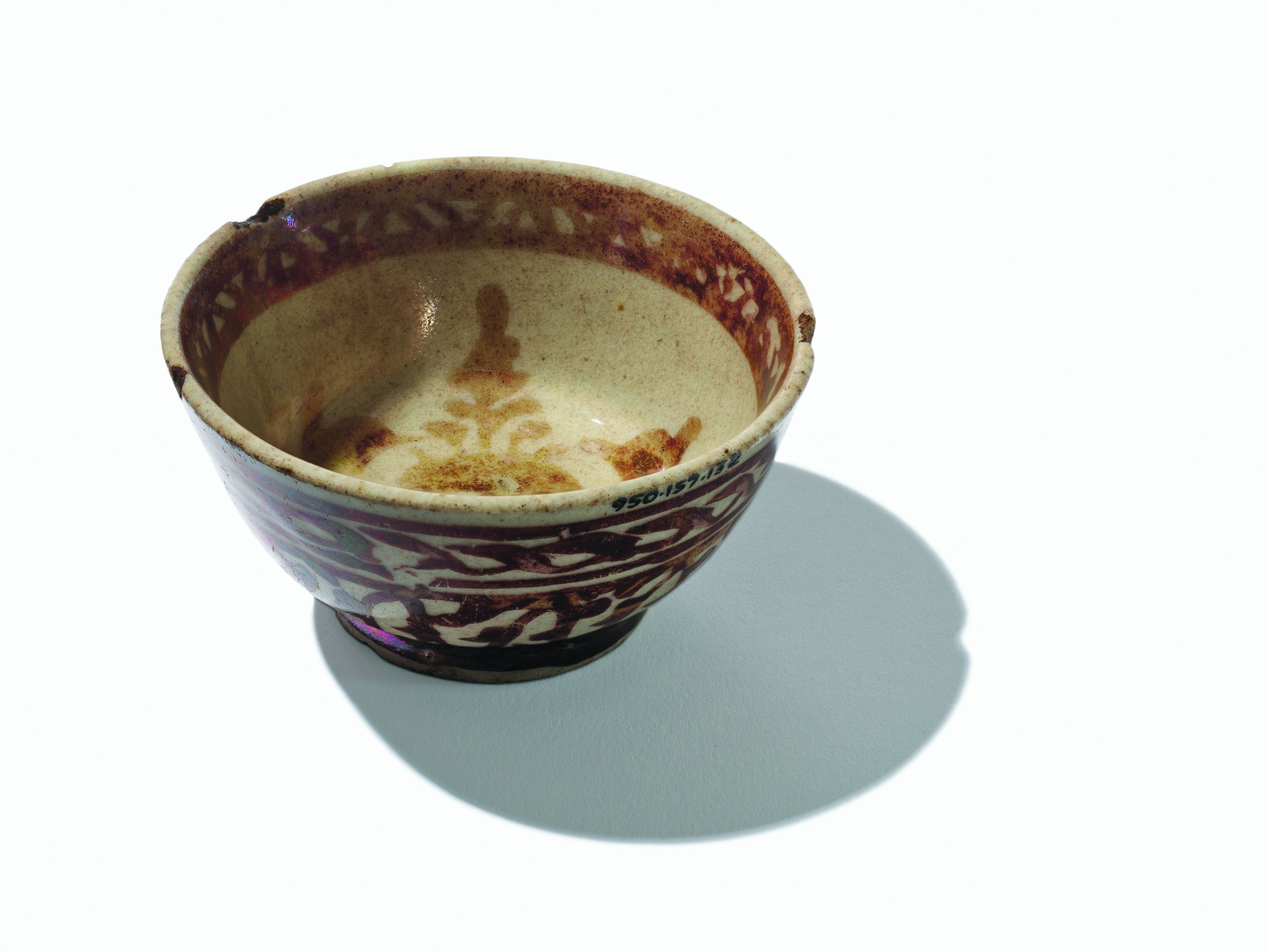 Bol en céramique avec des motifs floraux bruns et un intérieur beige, projetant une ombre sur un fond blanc.