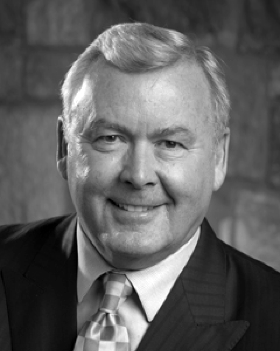 Portrait of an elderly man with light hair wearing a suit and tie, smiling at the camera.
