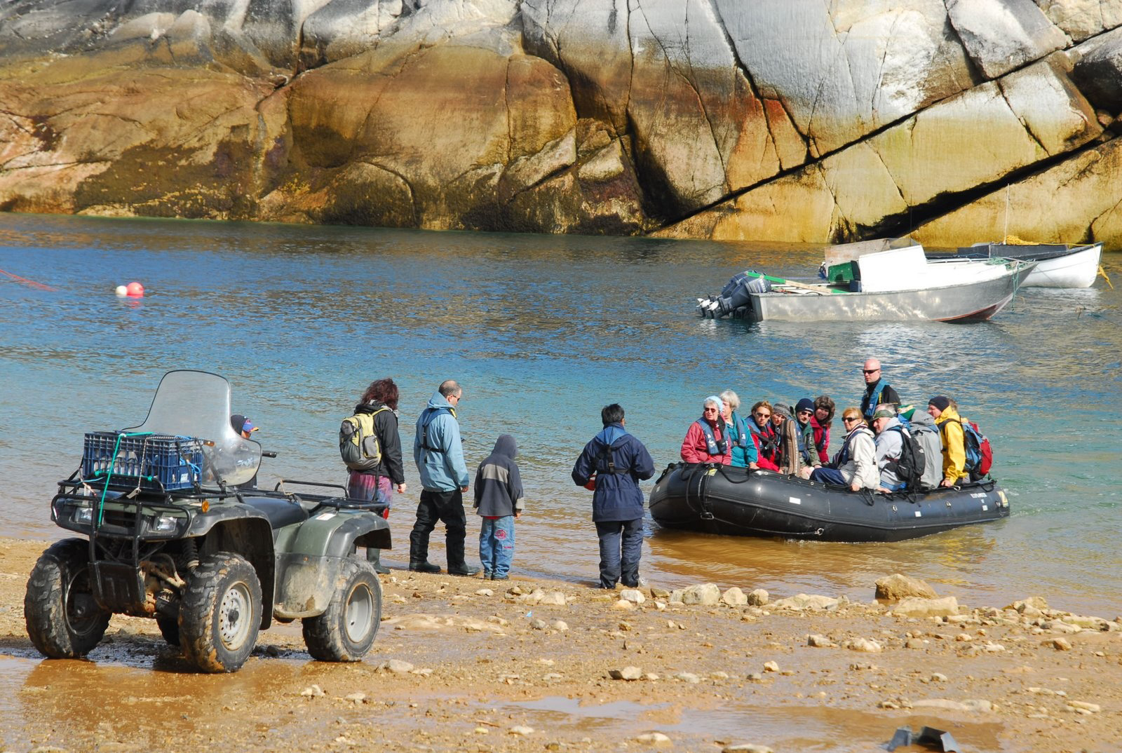 Un groupe de personnes dans un bateau Zodiac arrivant sur le rivage.
