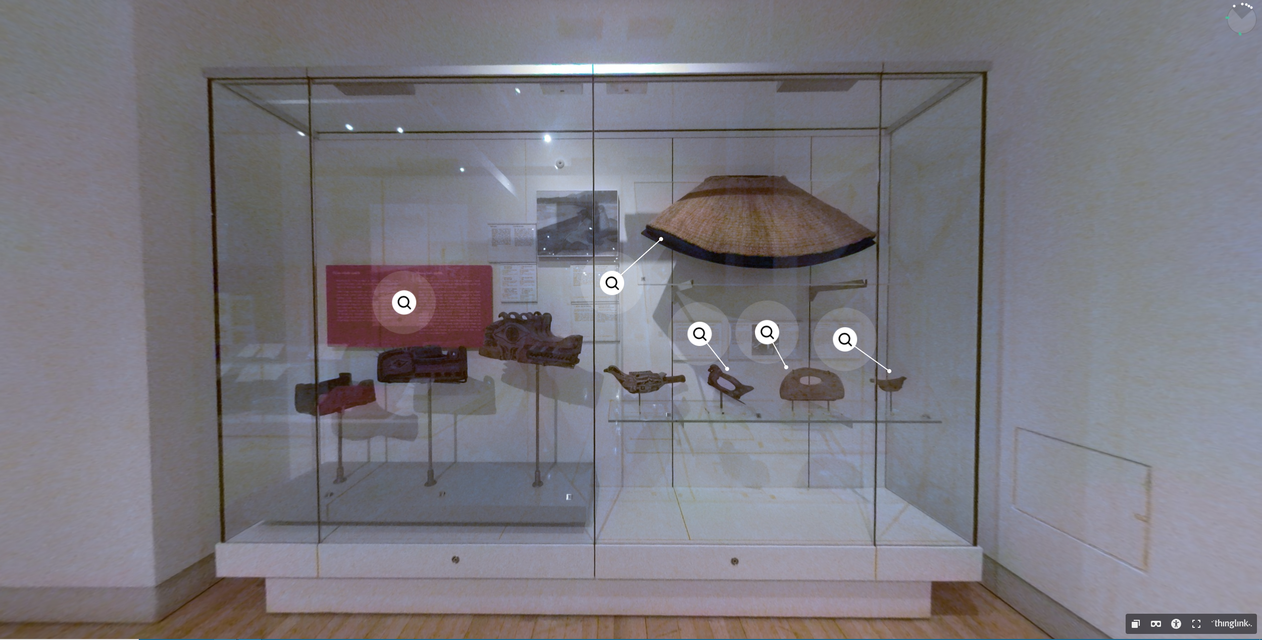 Vitrine d'un musée présentant de nombreux objets en cèdre, dont une cape, des masques et plusieurs outils.