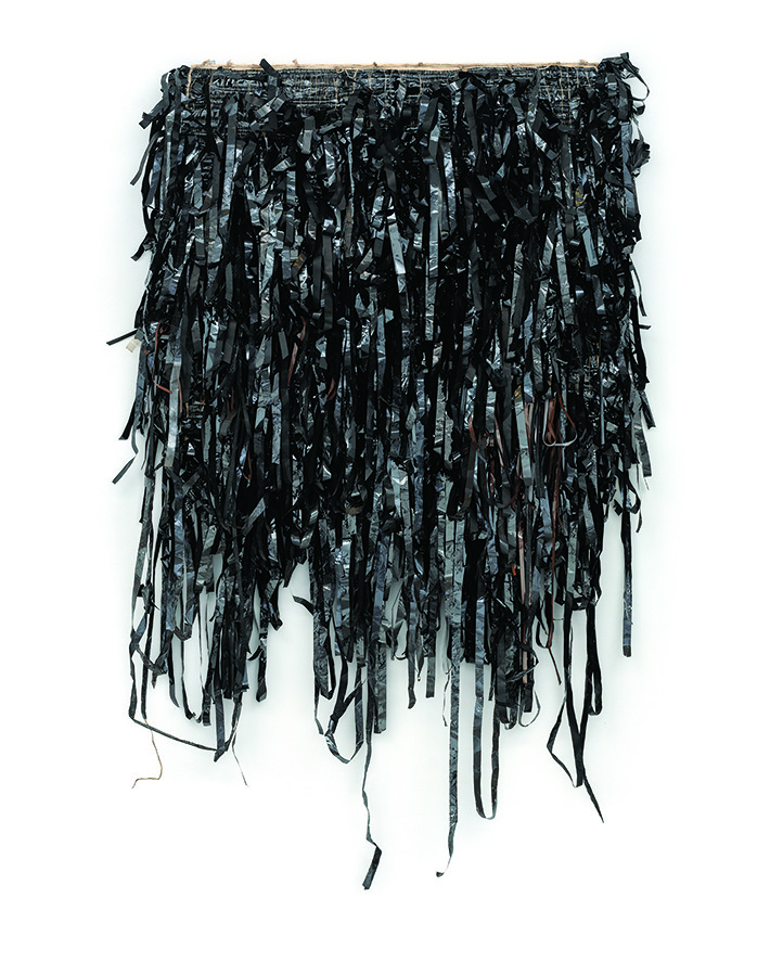 Une œuvre d'art textile composée de bandes noires, brillantes, coupées de manière irrégulière, densément superposées et pendantes.