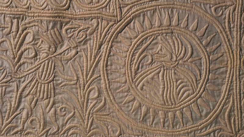 Intricate leaf and flower patterns carved in circular and curved designs on a textured stone surface.