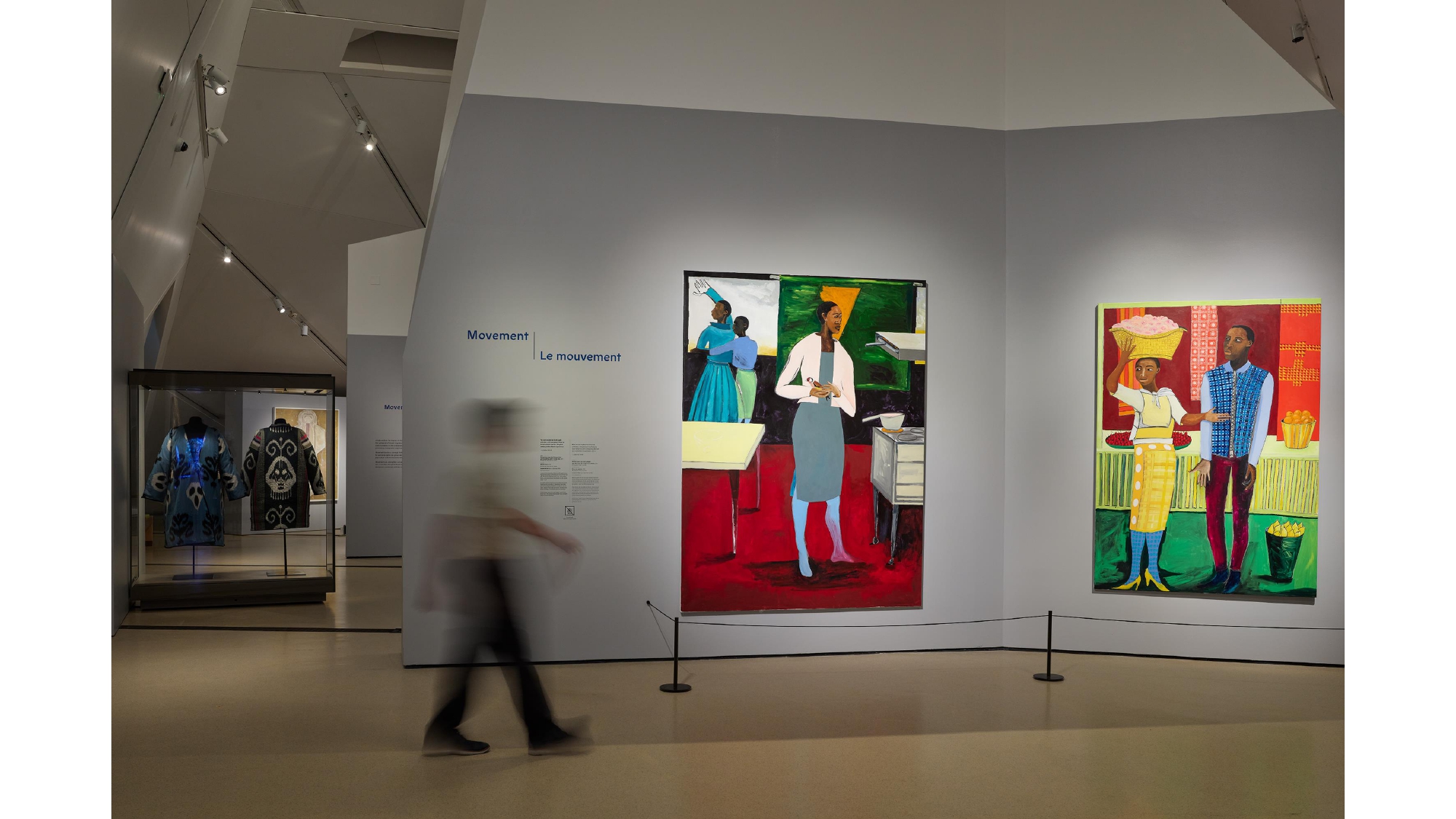 In-gallery image of 2 colourful paintings with person walking