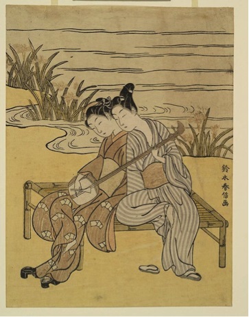 Two women seated closely together, dressed in traditional Japanese clothing, near a body of water with reeds.