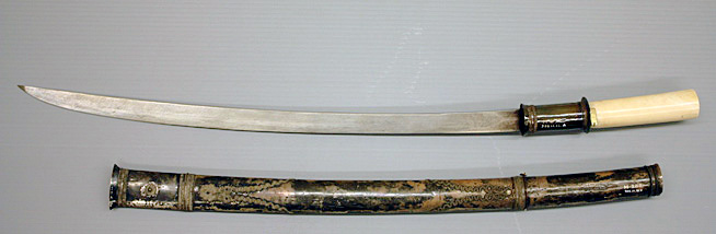 A Japanese katana sword with a white handle and a black lacquered scabbard decorated with gold designs.