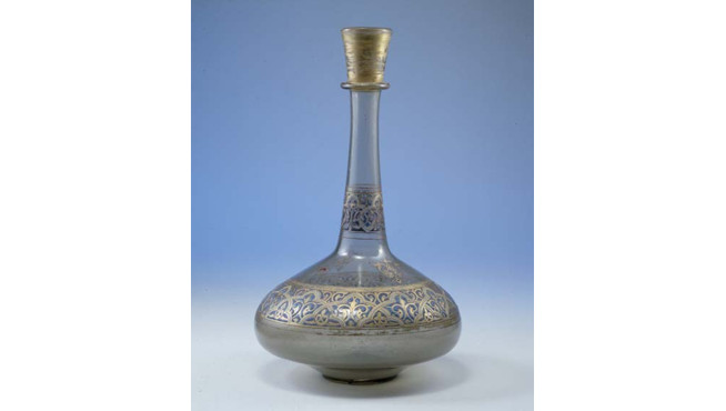 Glass bottle with a long narrow neck, decorated with a gold patterned band around the bulbous base and neck.