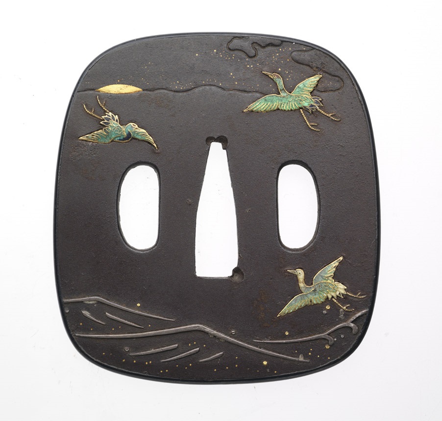 Square black tsuba with gold and green painted birds and a wavy line design near the bottom edge.