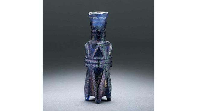 Glass figurine of a standing human figure with detailed facial features and geometric patterns on the body.