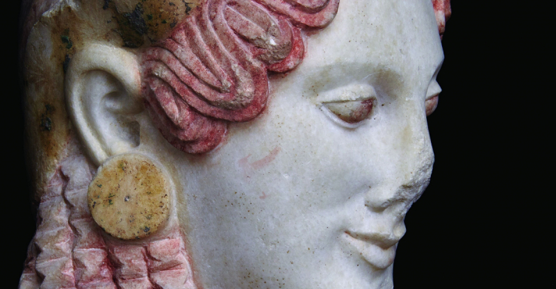 Close-up of a marble sculpture's face with detailed pink hair curls and a large circular earring.