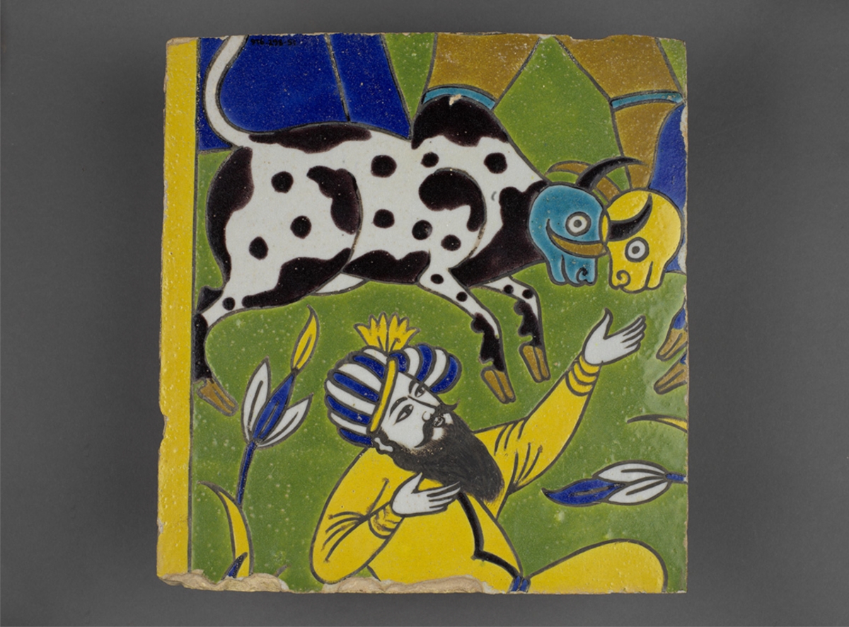 A ceramic tile showing a person in a yellow robe with a blue headpiece holding a flower, with a spotted black-and-white dog and a stylized blue bird above on a green and blue background.