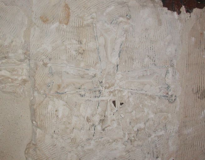 Carved stone relief featuring a central cross with floral and geometric patterns surrounding it.
