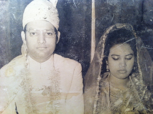 Portrait de mariage en noir et blanc d'un homme portant un turban et un costume traditionnels à côté d'une femme portant un saree et un voile.