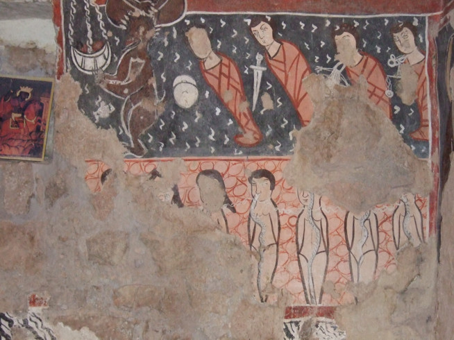 Ancient wall painting showing tribal figures with red body paint and black patterns, some holding curved objects.