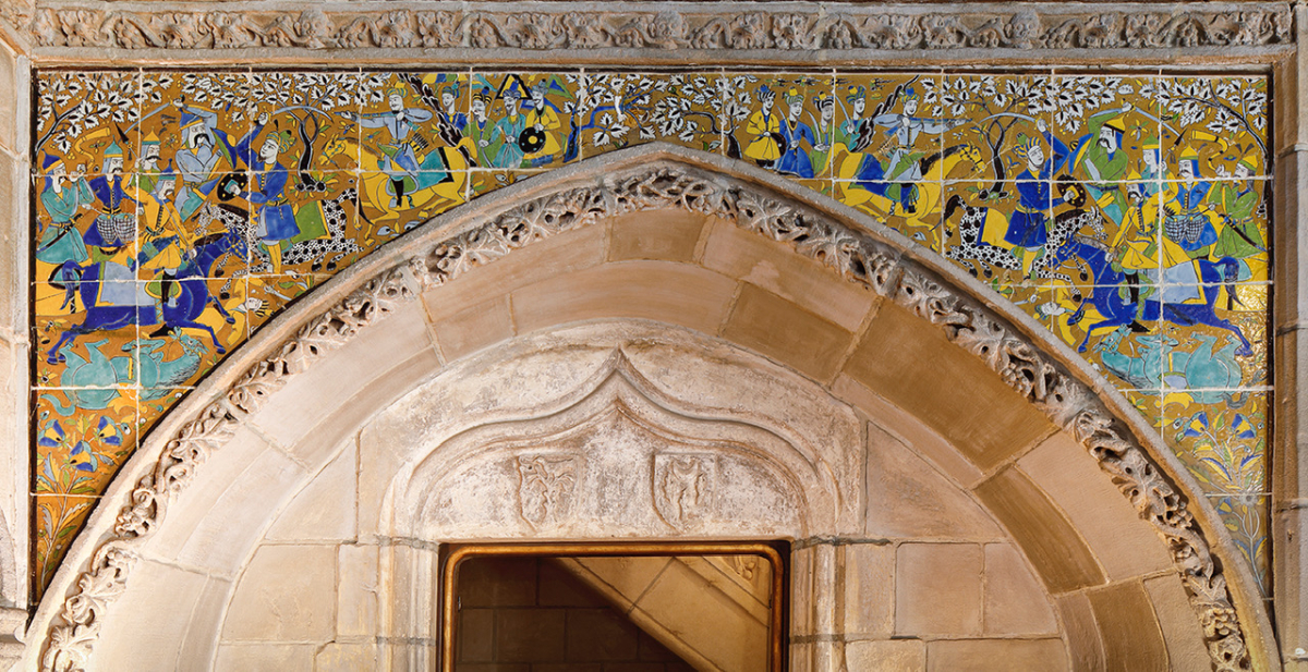 Decorative archway with a detailed blue, green, and gold tile frieze featuring mythical creatures above a carved stone lintel.