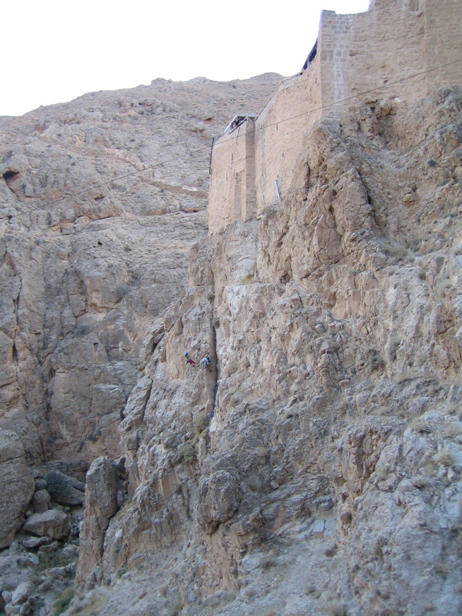 Ancient stone building partially built into a rocky desert cliffside.