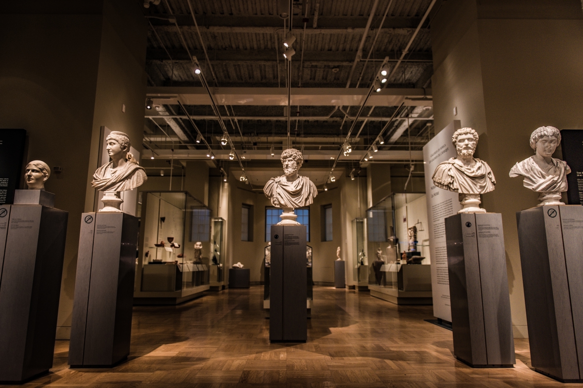 Gallery with seven marble busts of men arranged on tall pedestals in two rows inside the Royal Ontario Museum.