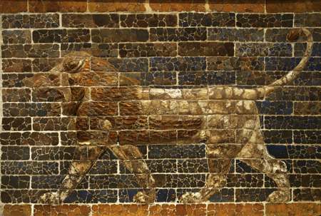 Bas-relief of a striding lion made of glazed brown bricks on a dark brick wall background.