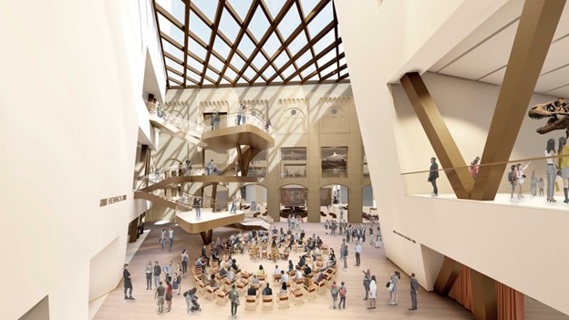 Large open museum atrium with a light-filled ceiling, spiral staircase, and scattered groups of visitors below.