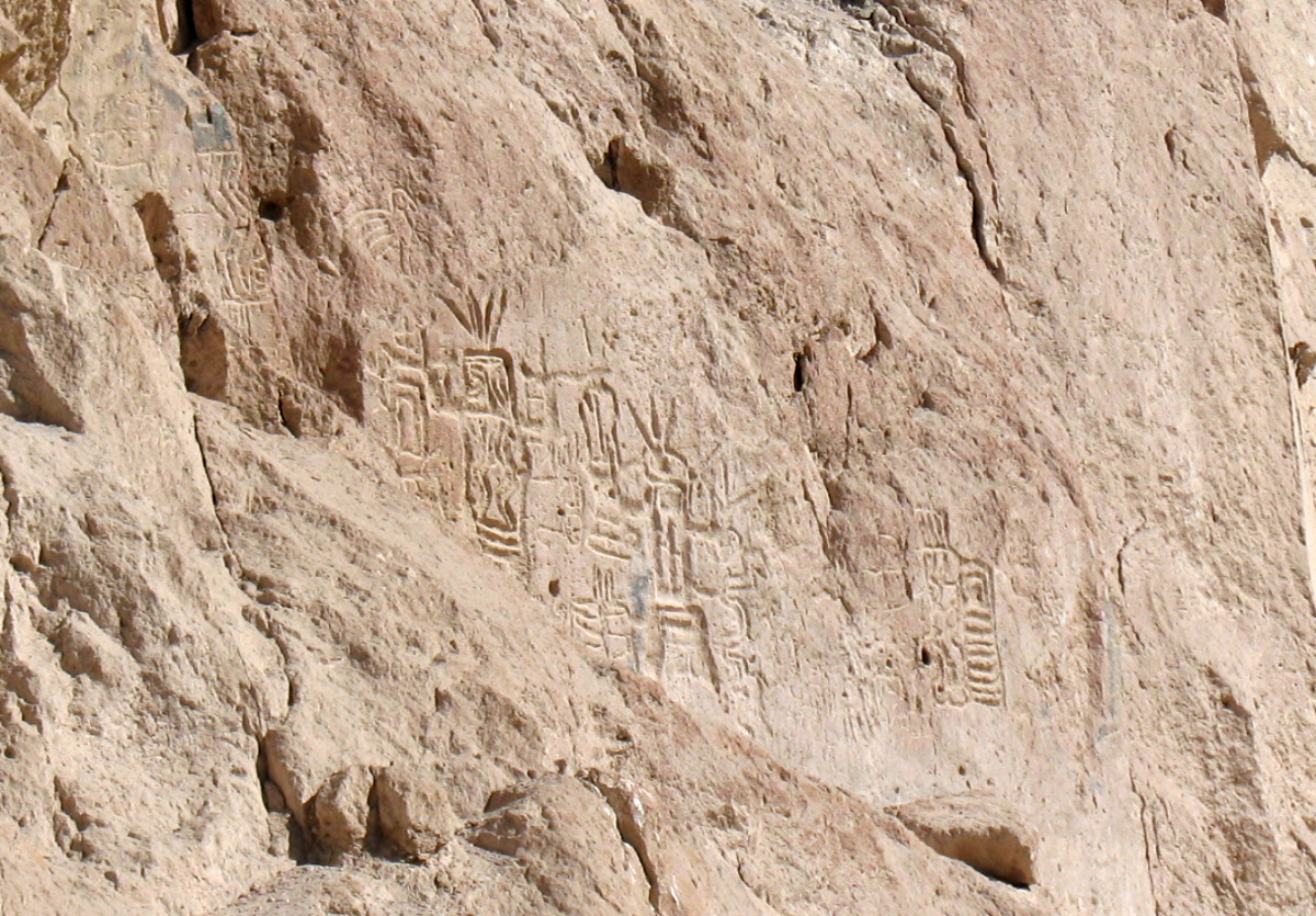 Ancient rock carvings of animals and human figures etched into a sandy cliff face.
