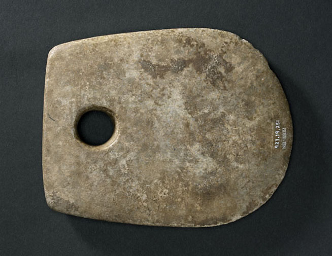 The image shows a rectangular stone with rounded corners and a large circular hole near one edge.