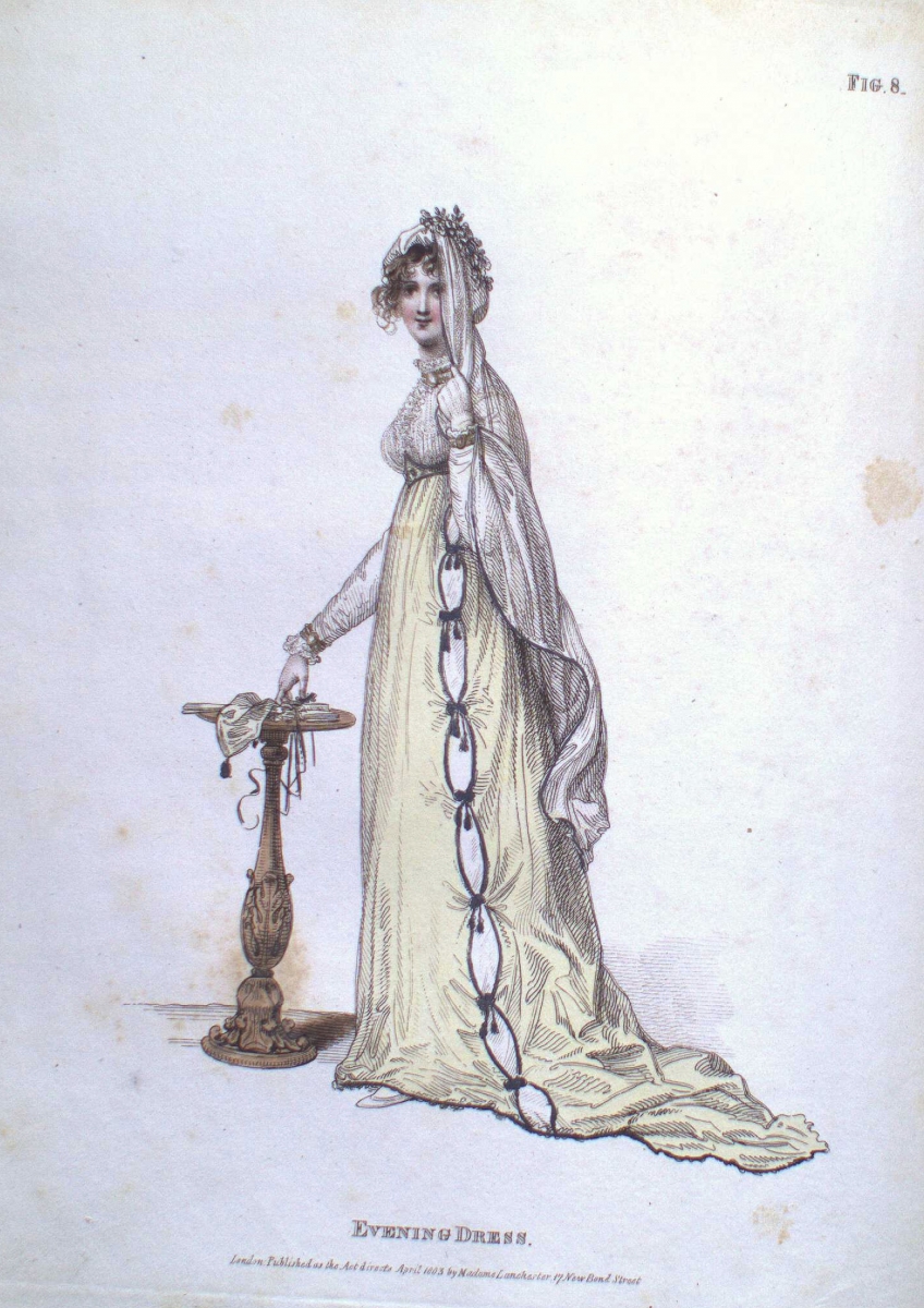 A woman in a long white flowing gown chained and shackled, holding a key, standing next to a pedestal with a skull.
