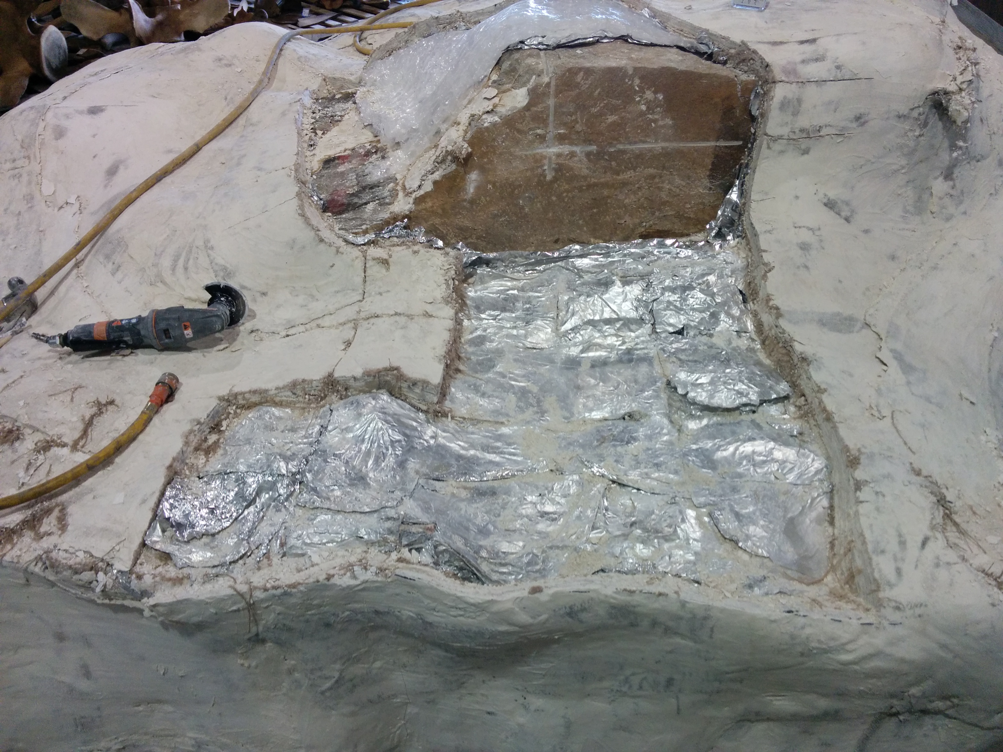Archaeological excavation site showing partially uncovered metallic artifacts embedded in sediment.