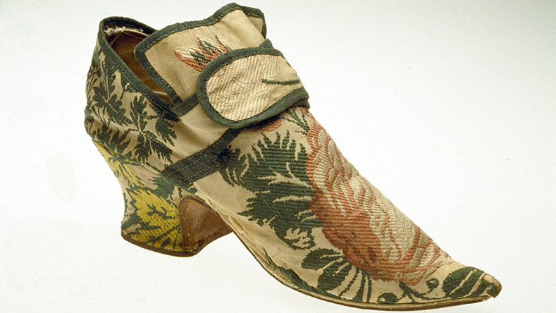 19th-century embroidered silk shoe with floral and leaf patterns in green, pink, and yellow tones.