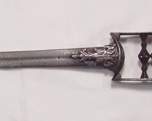 Metal two-pronged fork with ornamental handle featuring floral engravings.