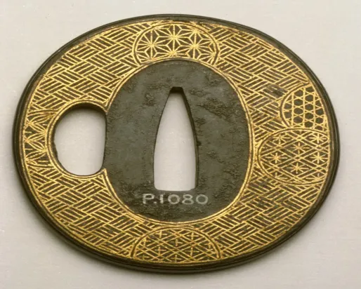 Circular Japanese sword guard with intricate gold and black geometric patterns and a central cutout.
