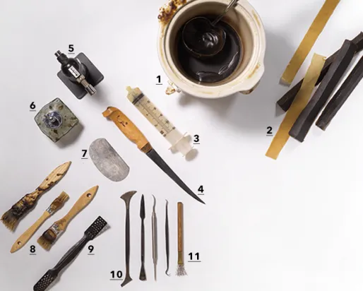 Divers outils traditionnels, dont des couteaux, des grattoirs et de petits objets sculptés, disposés sur une surface blanche à côté d'une tasse de café.