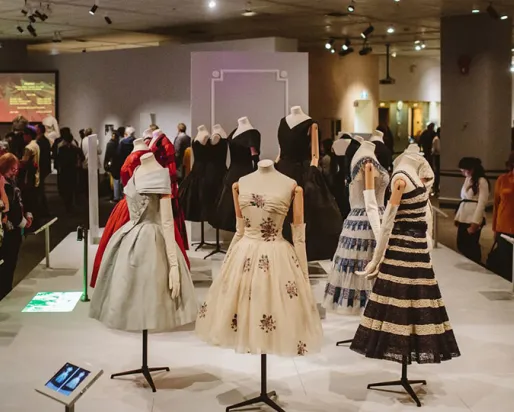 Des robes Dior exposées dans un espace muséal.

