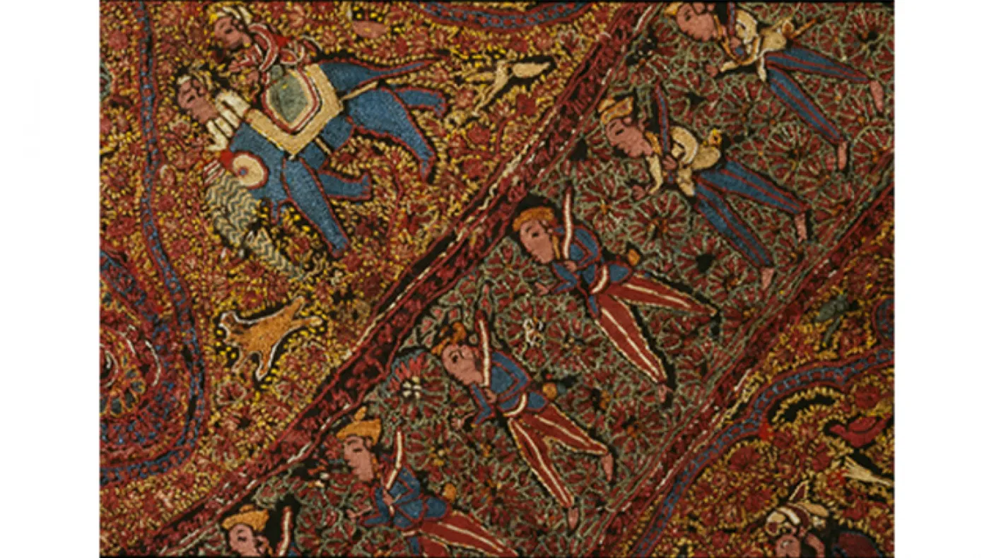 Textile coloré aux motifs complexes représentant des figures humaines, des éléphants et des motifs floraux sur un fond brun-rouge.