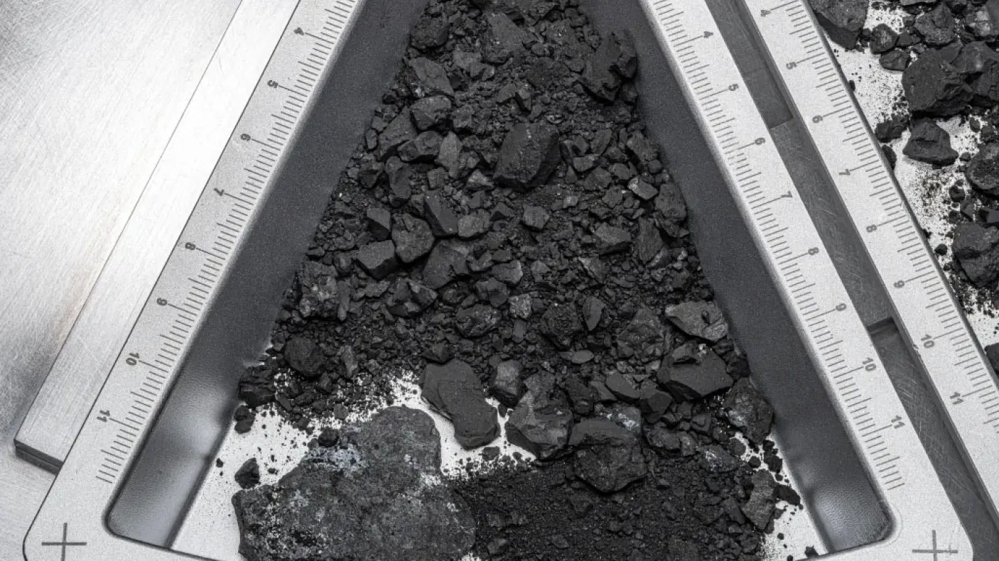 OREX 44 etched on a triangular metal frame holding dark soil and rock fragments.