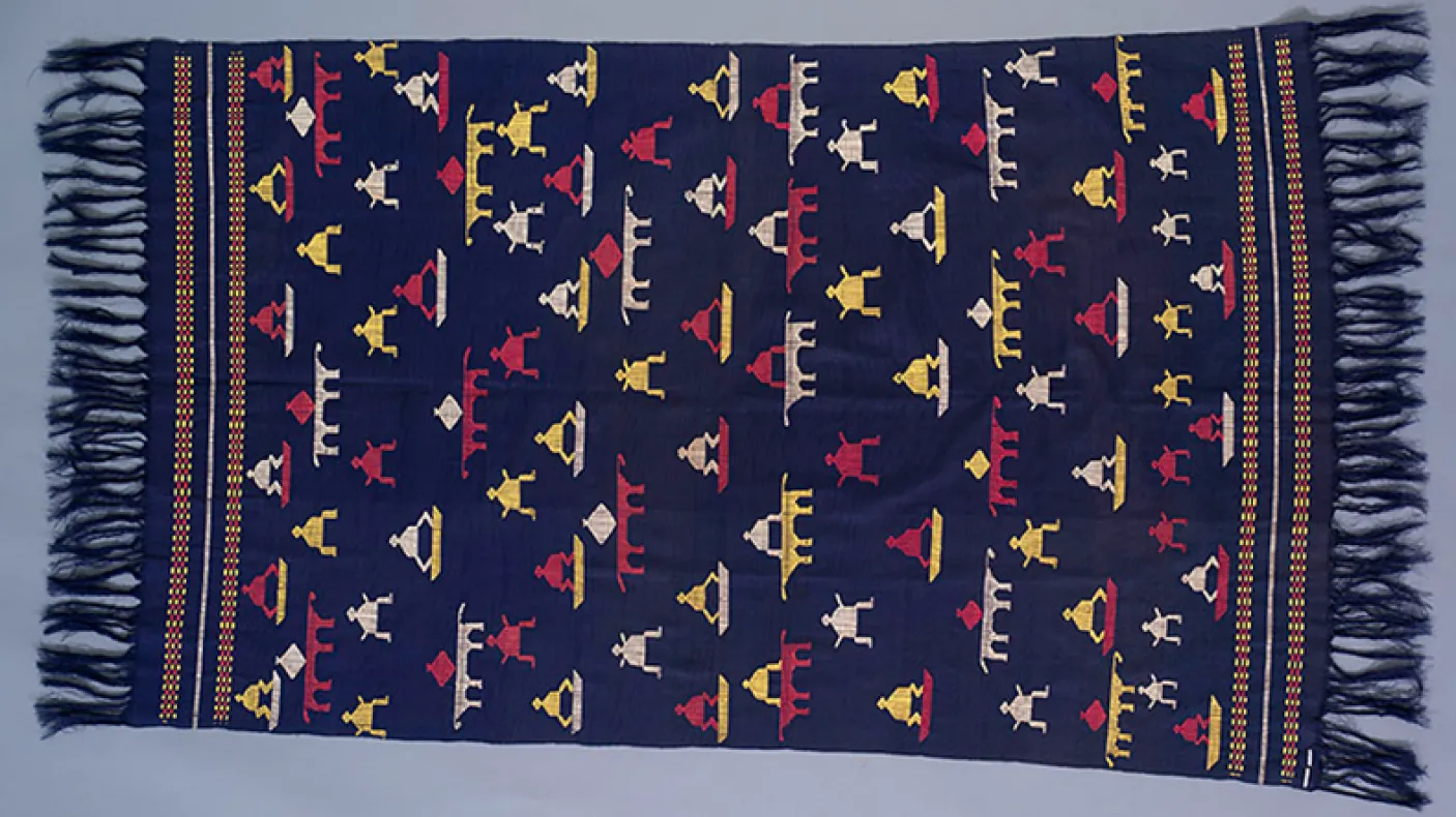 Textile tissé avec un fond bleu foncé et des motifs géométriques en rouge, jaune, blanc et bleu avec des bords frangés.