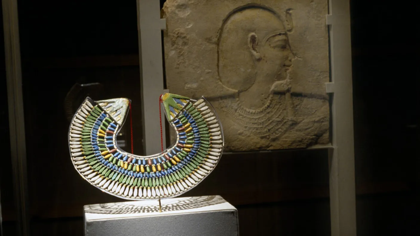 Gallery shot of Eye of the Beholder with collar and relief sculpture in foreground under spotlight, W. Garfield Weston Exhibition Hall
