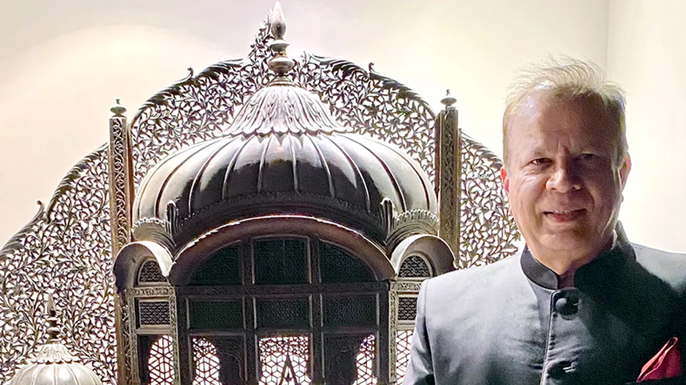 An ornate silver ceremonial object with intricate patterns beside a man in a dark jacket.