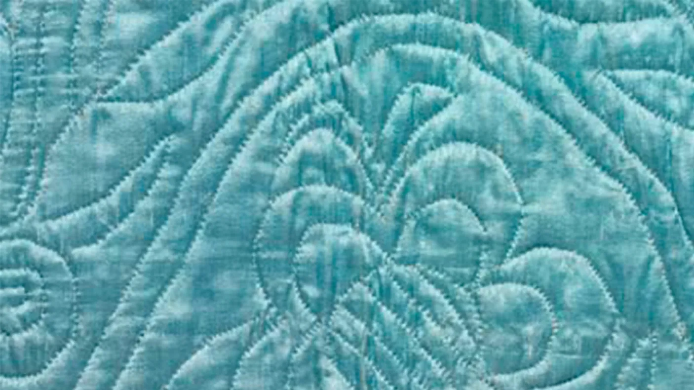 Gros plan d'un tissu bleu clair avec des motifs piqués comprenant un papillon et des lignes symétriques.