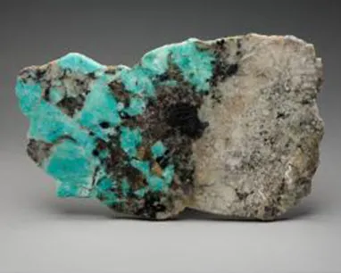 Rough turquoise and gray mineral rock with black specks.