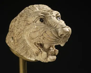 Carved ivory lion head with open mouth showing teeth and detailed mane.