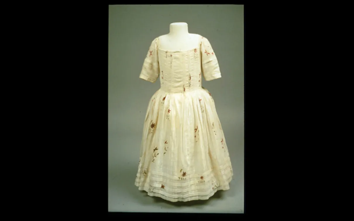 Robe de couleur crème avec des manches au coude et une jupe ample décorée d'un subtil motif floral.
