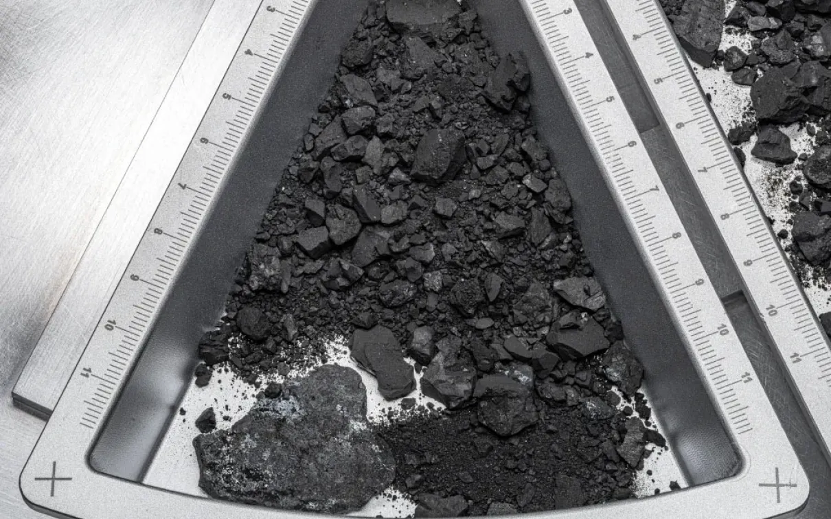 OREX 44 etched on a triangular metal frame holding dark soil and rock fragments.