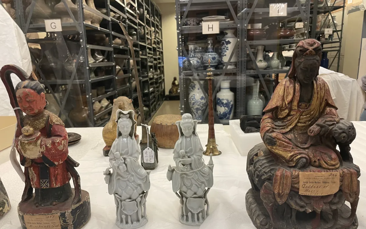 Two seated figurines on either side of four small standing white statues arranged in a row.