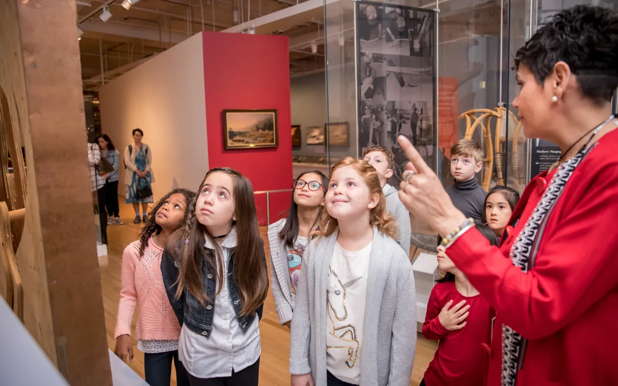 Un groupe d'enfants écoute un guide expliquer une exposition.