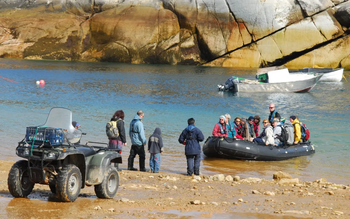 Un groupe de personnes dans un bateau Zodiac arrivant sur le rivage.