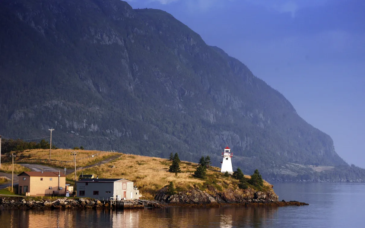 Un phare avec une montagne en arrière-plan.