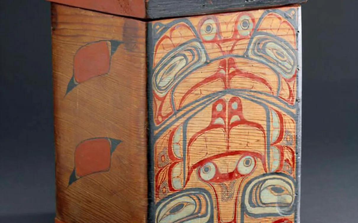 Une boîte en bois rouge peinte de motifs rouges, noirs et blancs.