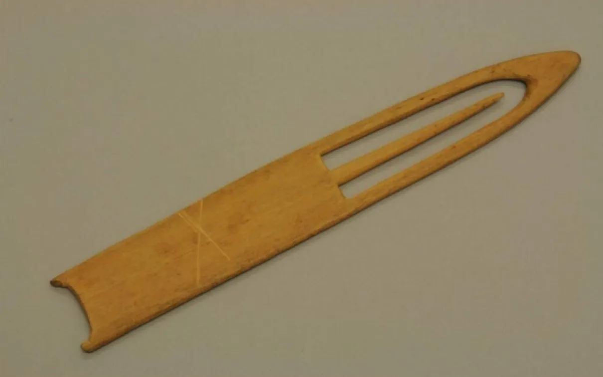 Pièce de bois sculptée avec une pointe et une aiguille pointue à l'intérieur d'un espace découpé à la pointe.