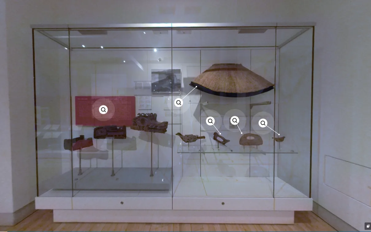 Vitrine d'un musée présentant de nombreux objets en cèdre, dont une cape, des masques et plusieurs outils.